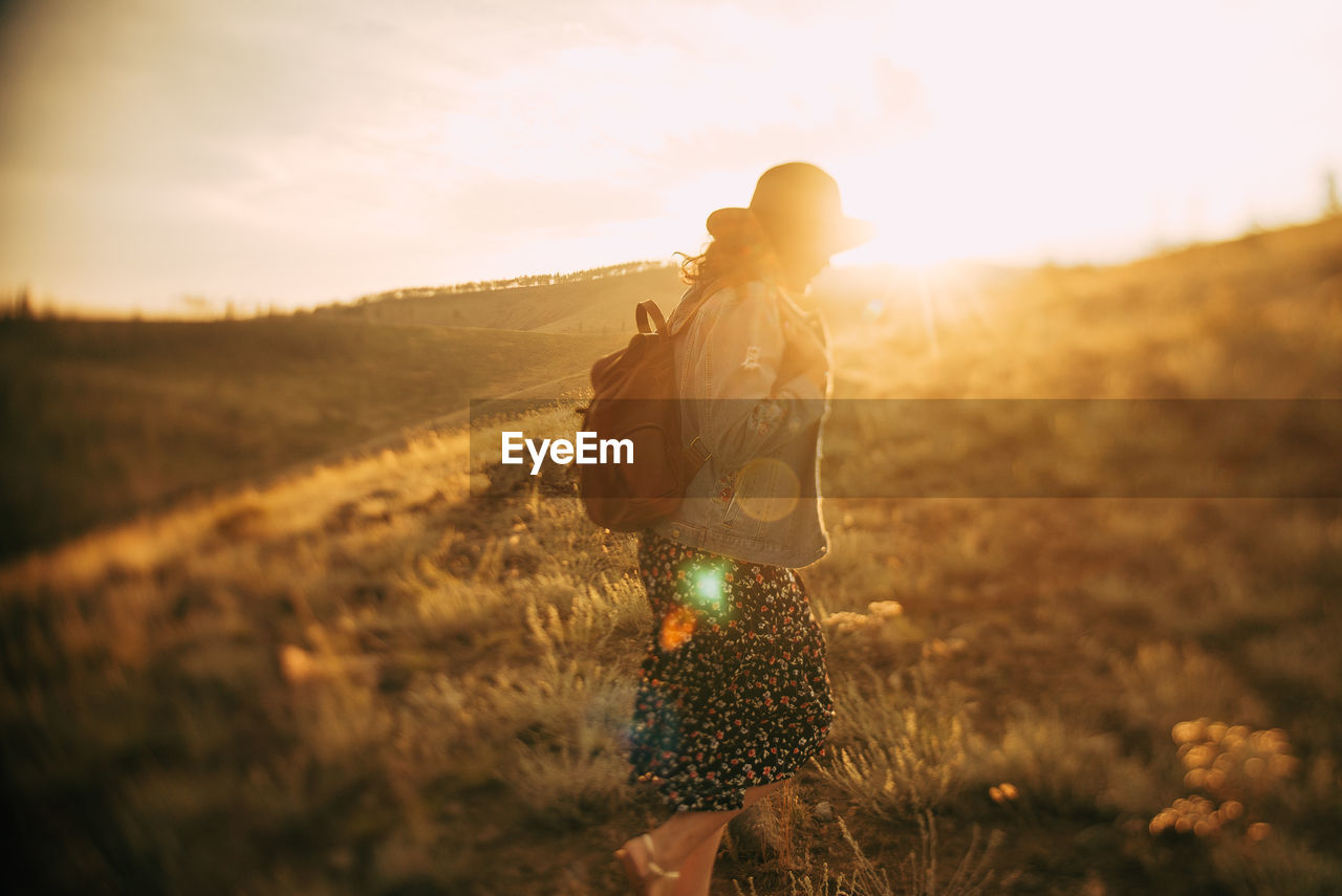 Side view of woman walking on land against sky