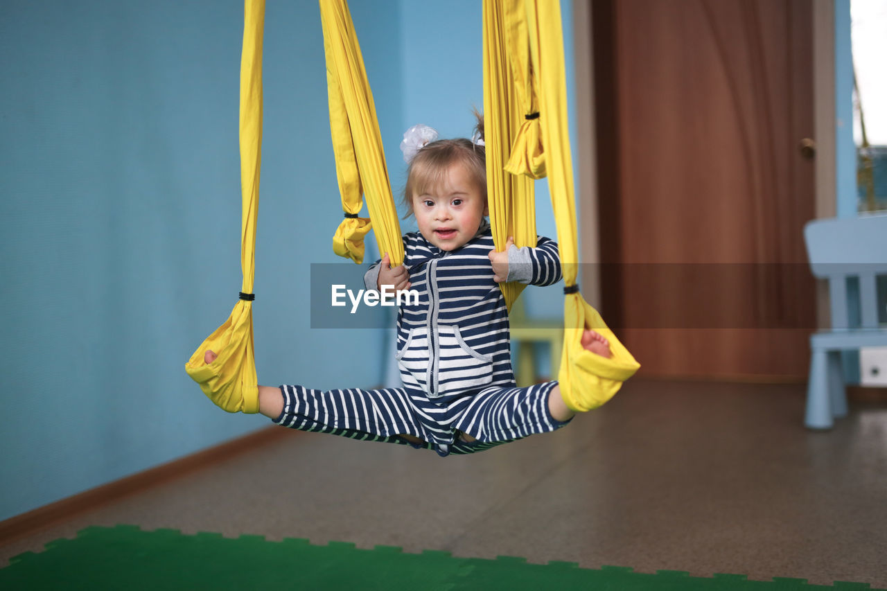 rear view of boy swinging on slide at home