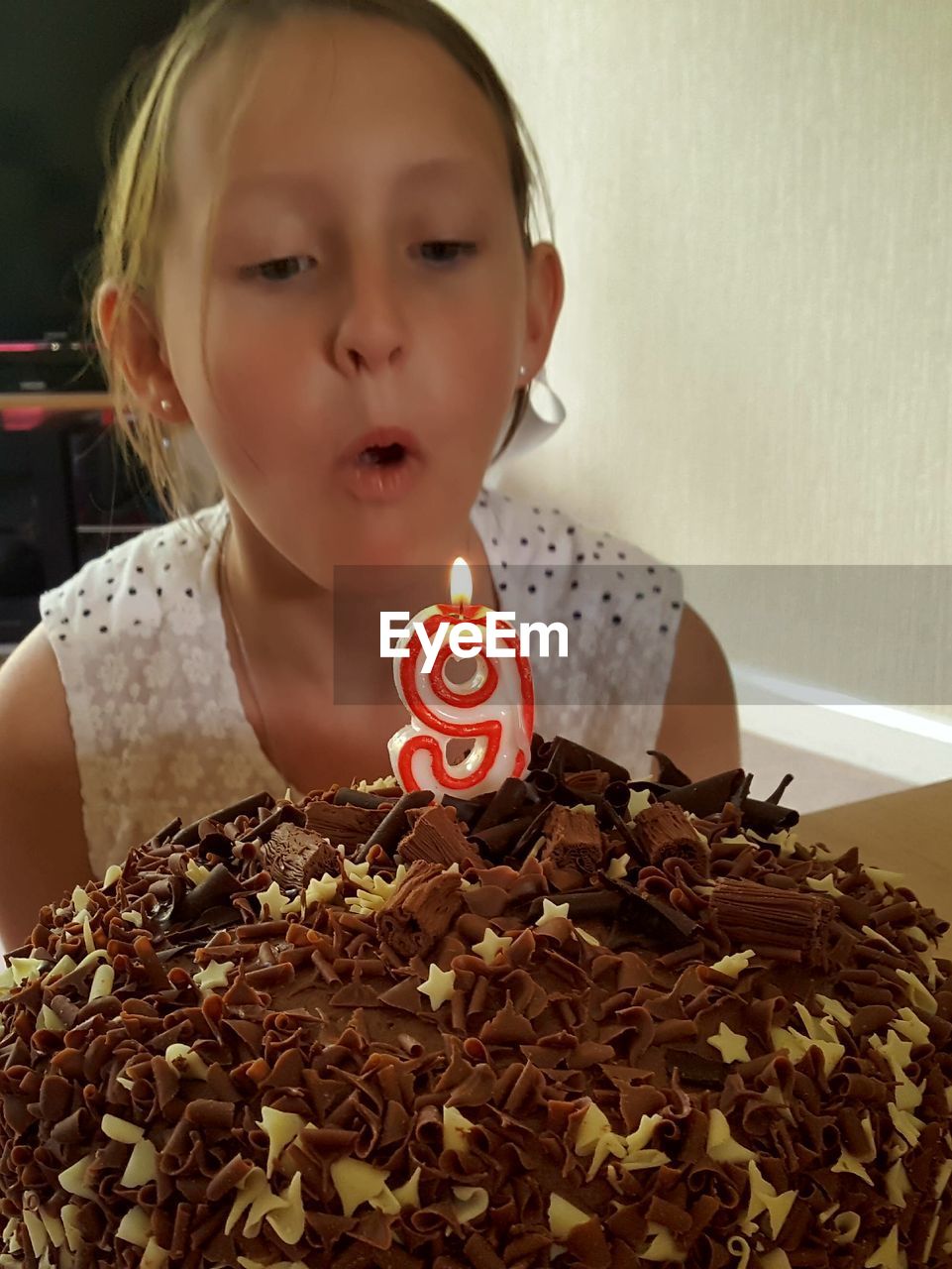 Close-up of girl blowing candle on birthday cake at home