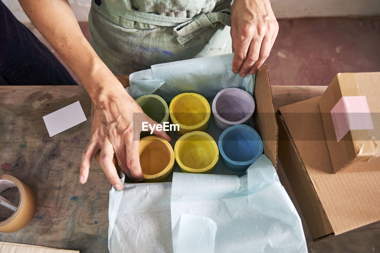 Female store owner arranging colorful design concretes in box at workshop