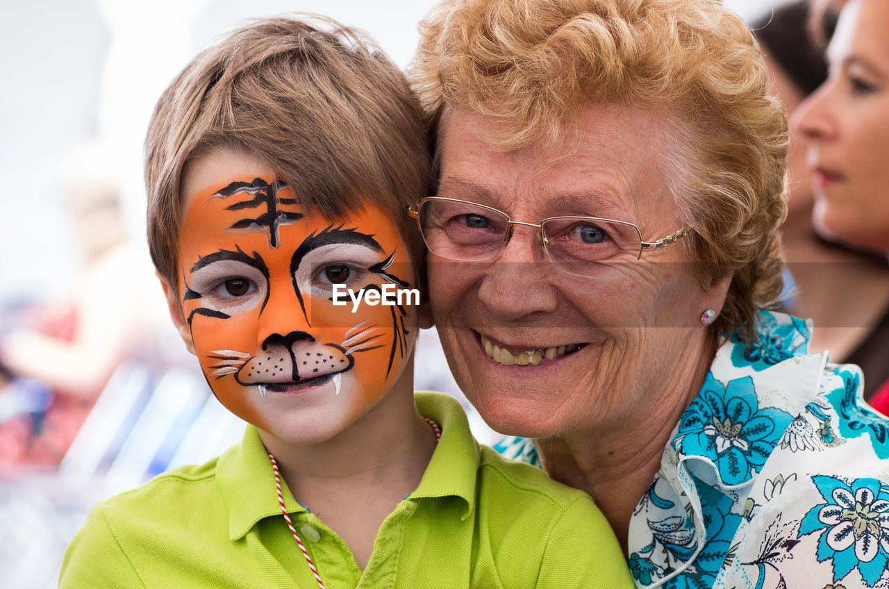 Portrait of grandson with face paint by happy grandmother