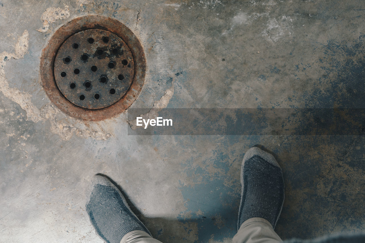 Low section of man standing by sewer in basement