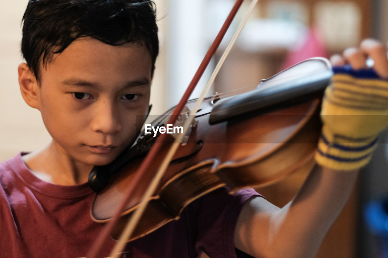 Close-up of cute boy playing violin