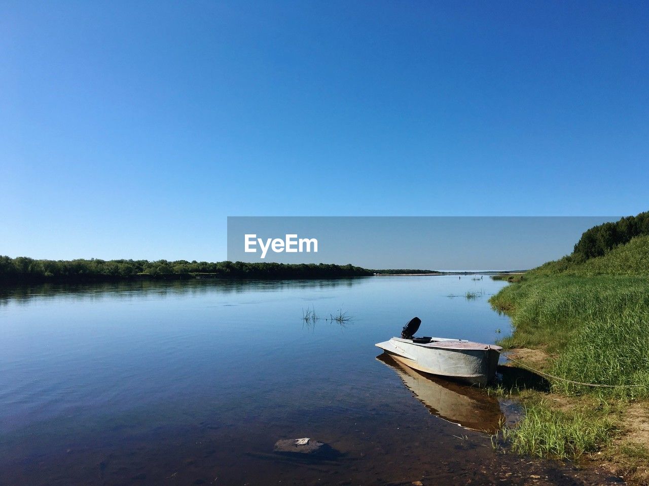 water, sky, nautical vessel, reflection, lake, transportation, nature, clear sky, scenics - nature, tranquility, shore, beauty in nature, blue, boat, tranquil scene, mode of transportation, day, body of water, plant, tree, non-urban scene, vehicle, land, reservoir, beach, no people, copy space, bay, landscape, travel, rowboat, outdoors, environment, boating, moored, canoe, travel destinations, idyllic, watercraft, sunny, holiday, mountain, forest