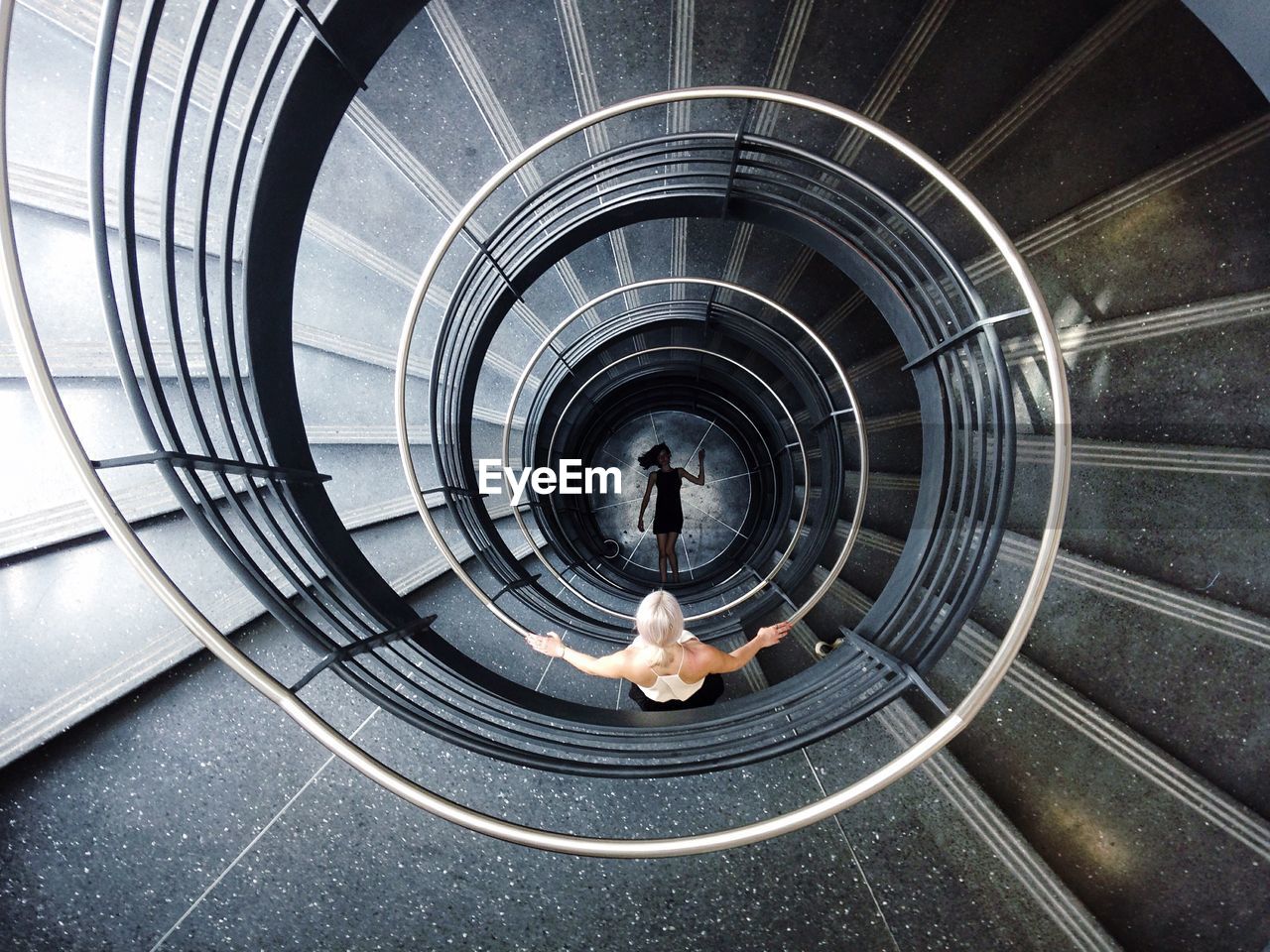 Directly above shot of woman standing on spiral staircase looking at dead person