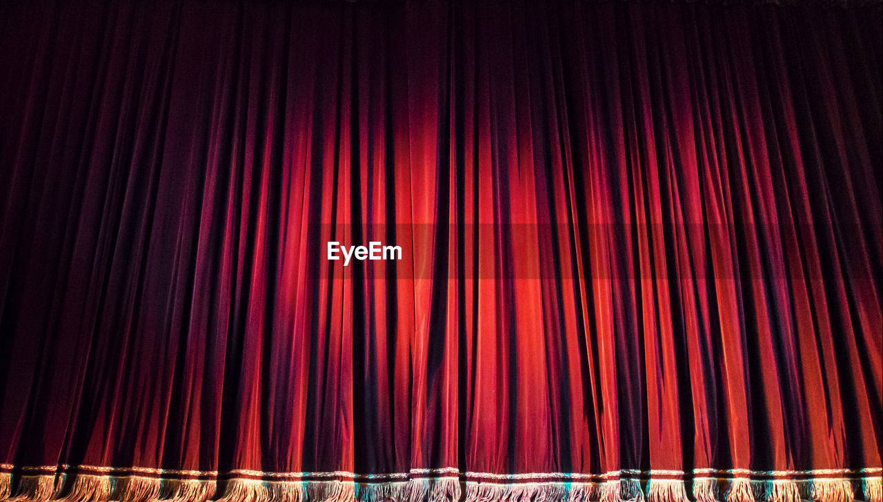 Red closed curtain with spotlight in theater