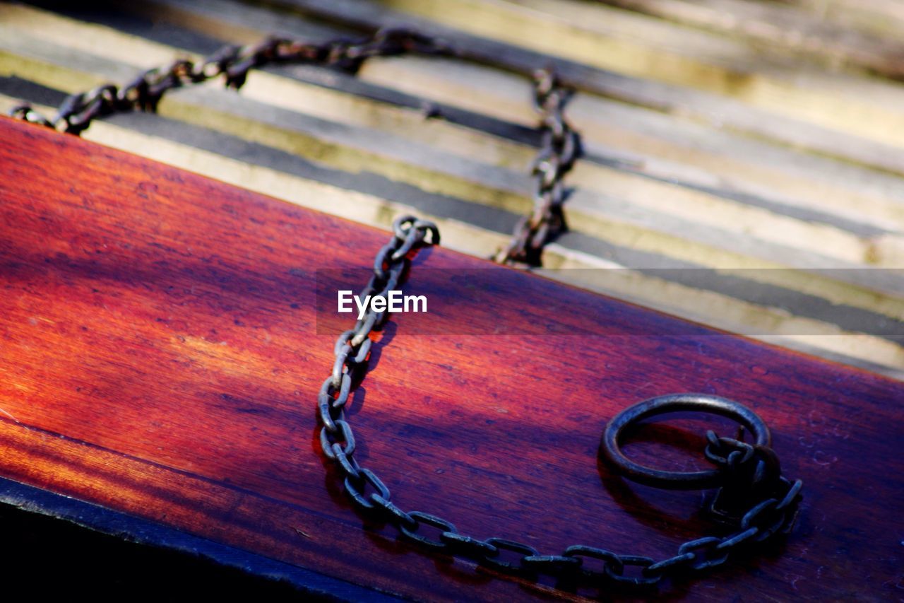 CLOSE-UP OF METAL CHAIN ON WOOD