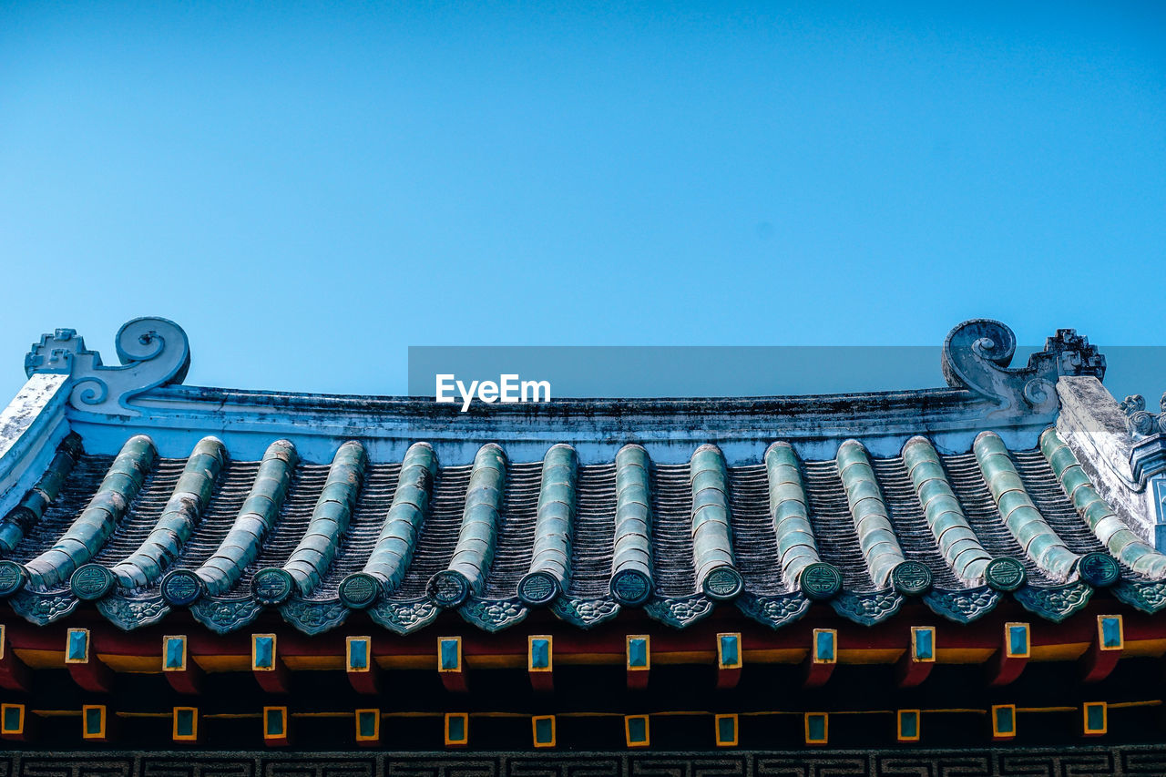 Low angle view of temple roof against clear blue sky