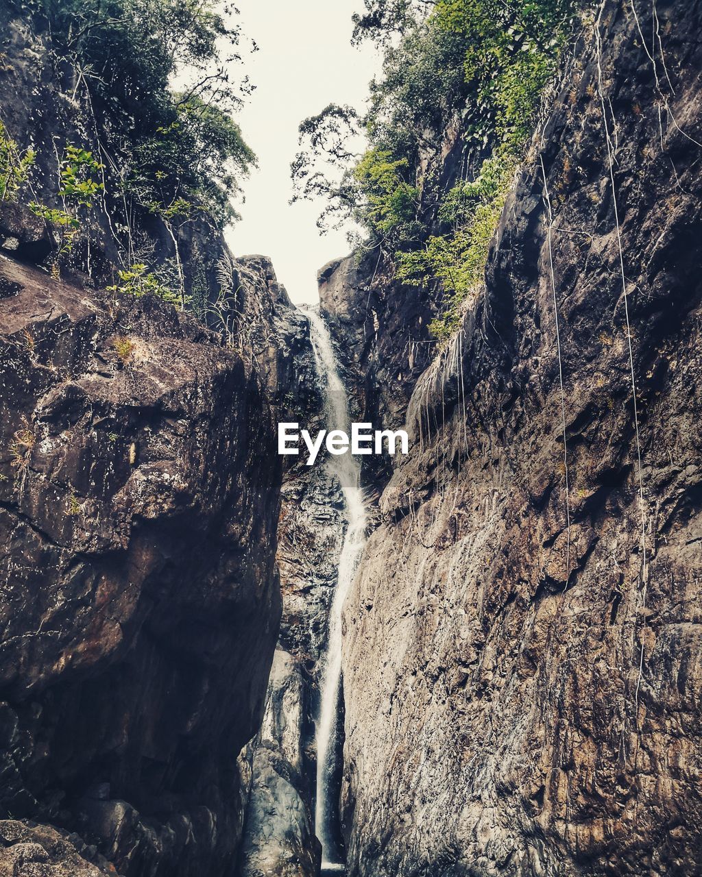 LOW ANGLE VIEW OF WATERFALL ON MOUNTAIN