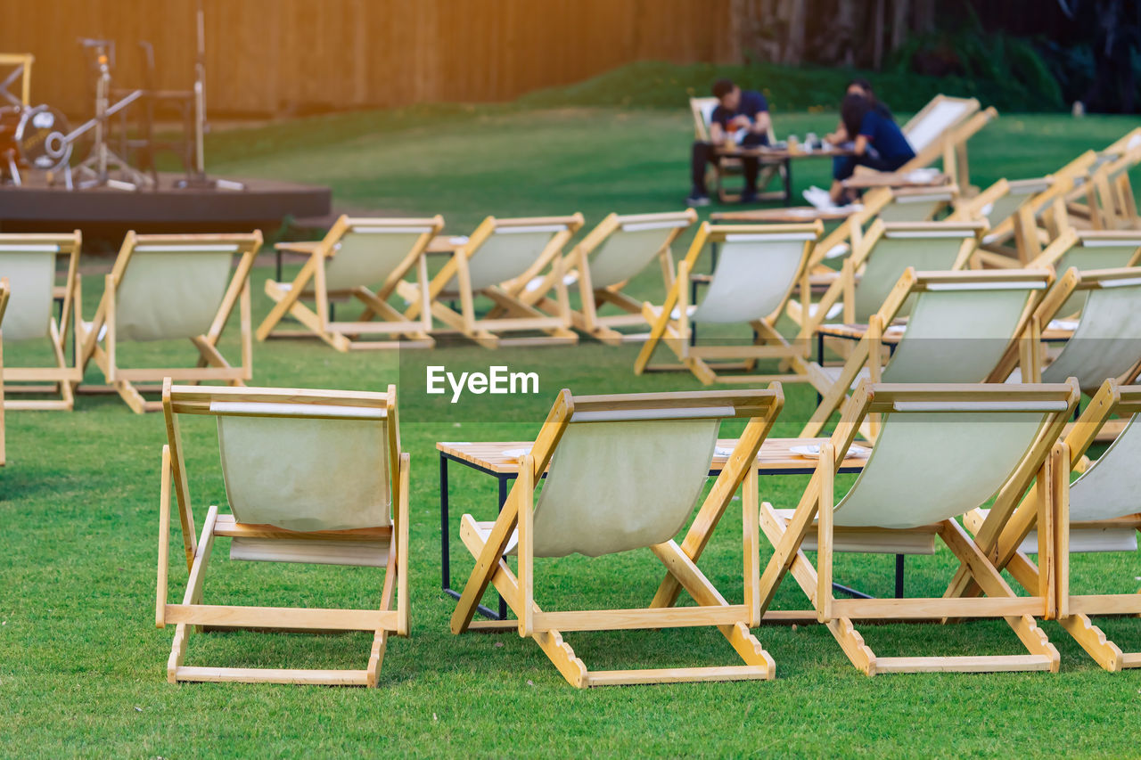Many white deck chairs with tables for dinner in lawn is surrounded by shady green grass 