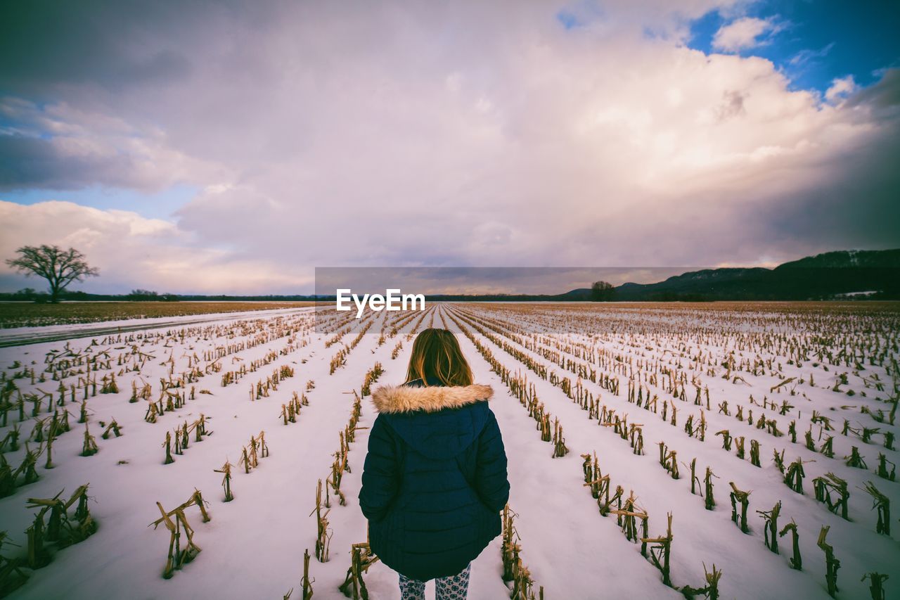 Rear view of girl on agricultural field during winter