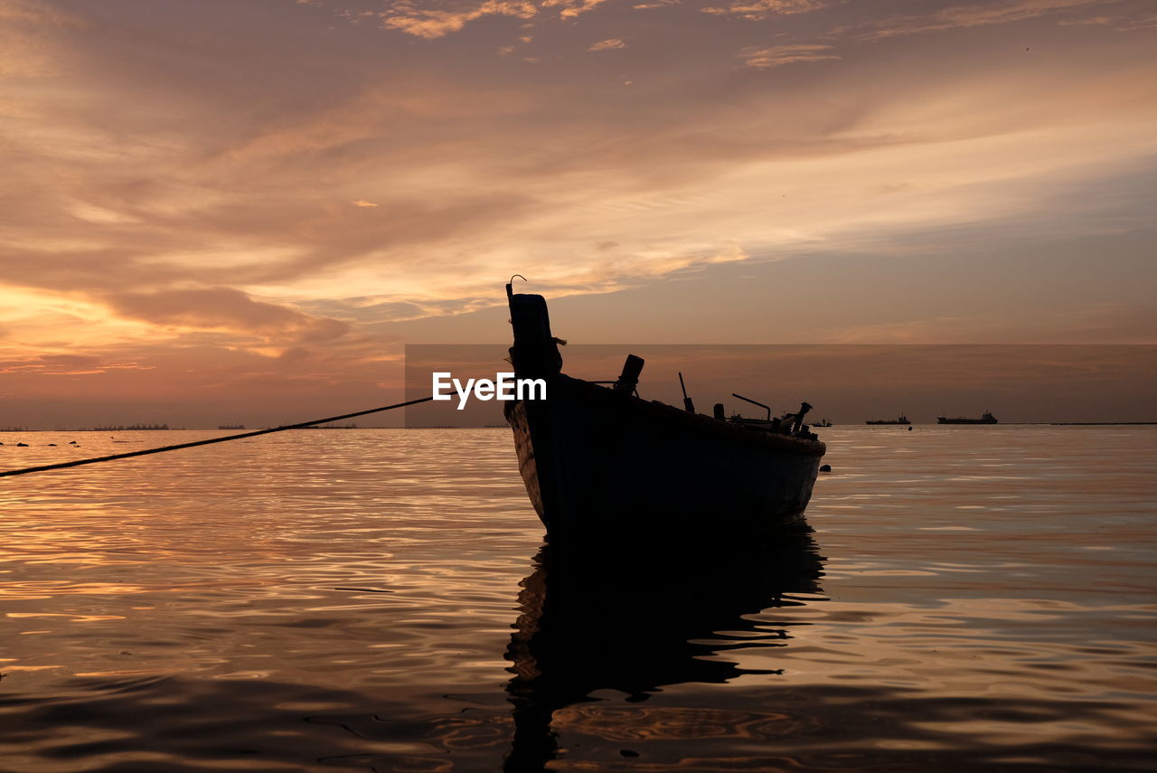 FISHING BOAT IN SEA AGAINST ORANGE SKY