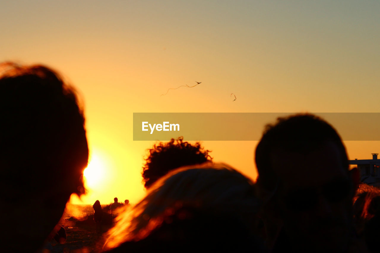 Close-up of silhouette people at beach during sunset