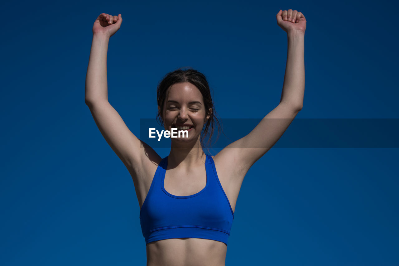 Young woman gesturing while standing against blue background