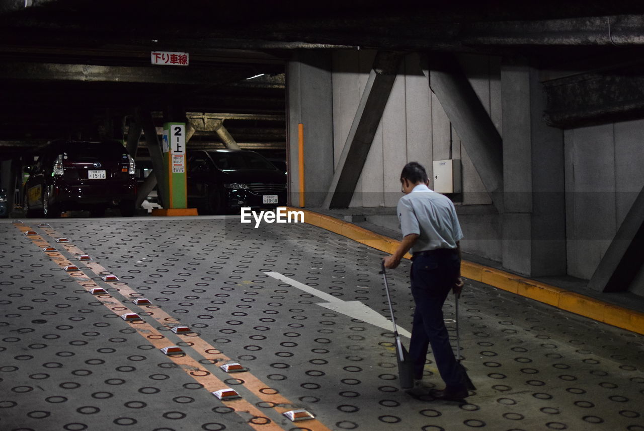 FULL LENGTH OF MAN STANDING IN CORRIDOR OF BUILDING