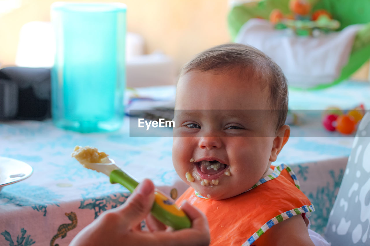 Parent feeding cute baby at home