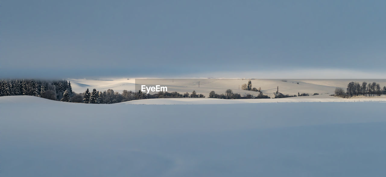 Scenic view of snow covered mountains against blue sky