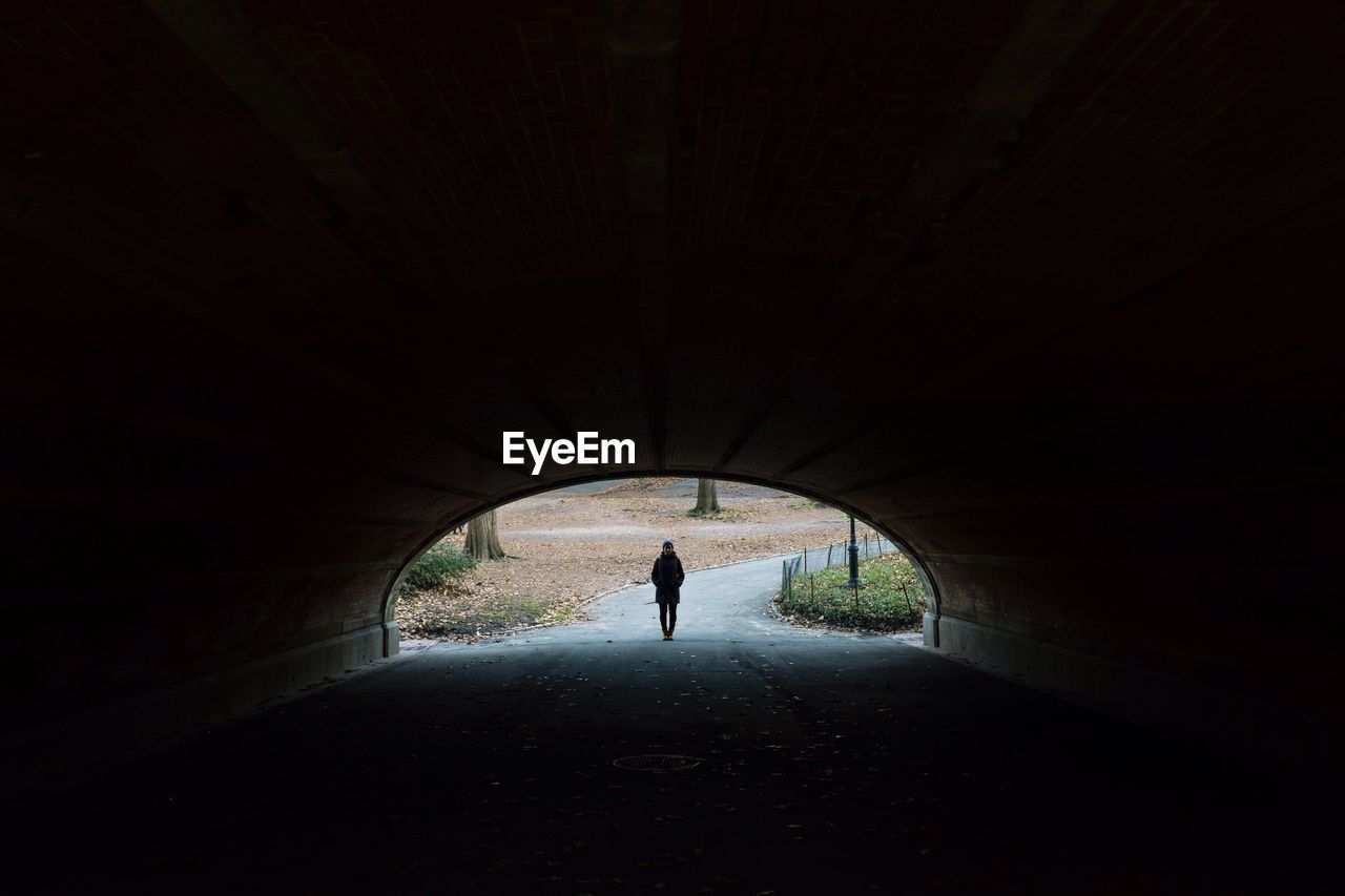 Woman standing at archway seen from tunnel