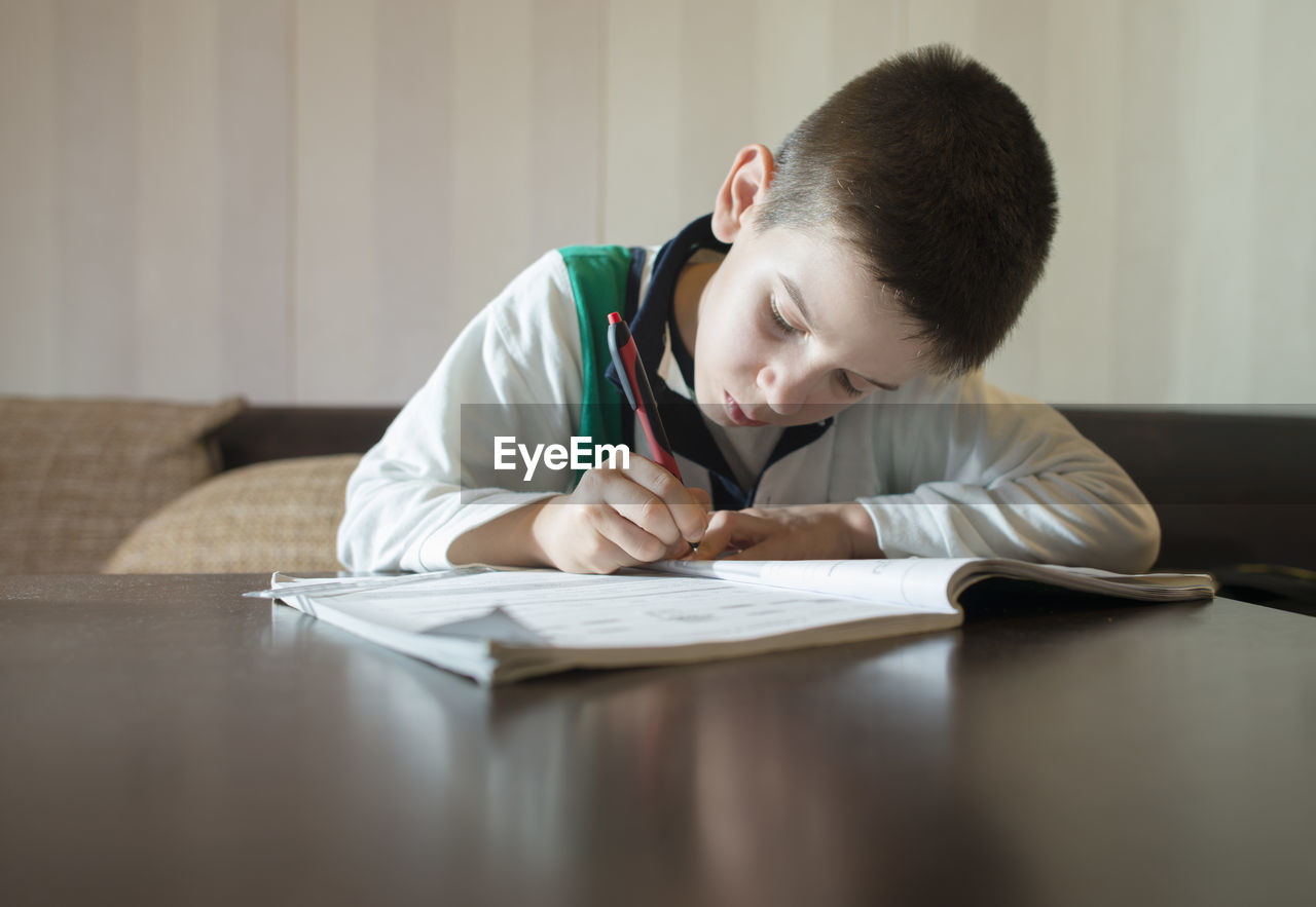 SIDE VIEW OF BOY SITTING ON BOOK