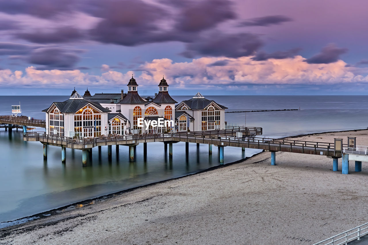 PIER AMIDST SEA AGAINST SKY DURING SUNSET