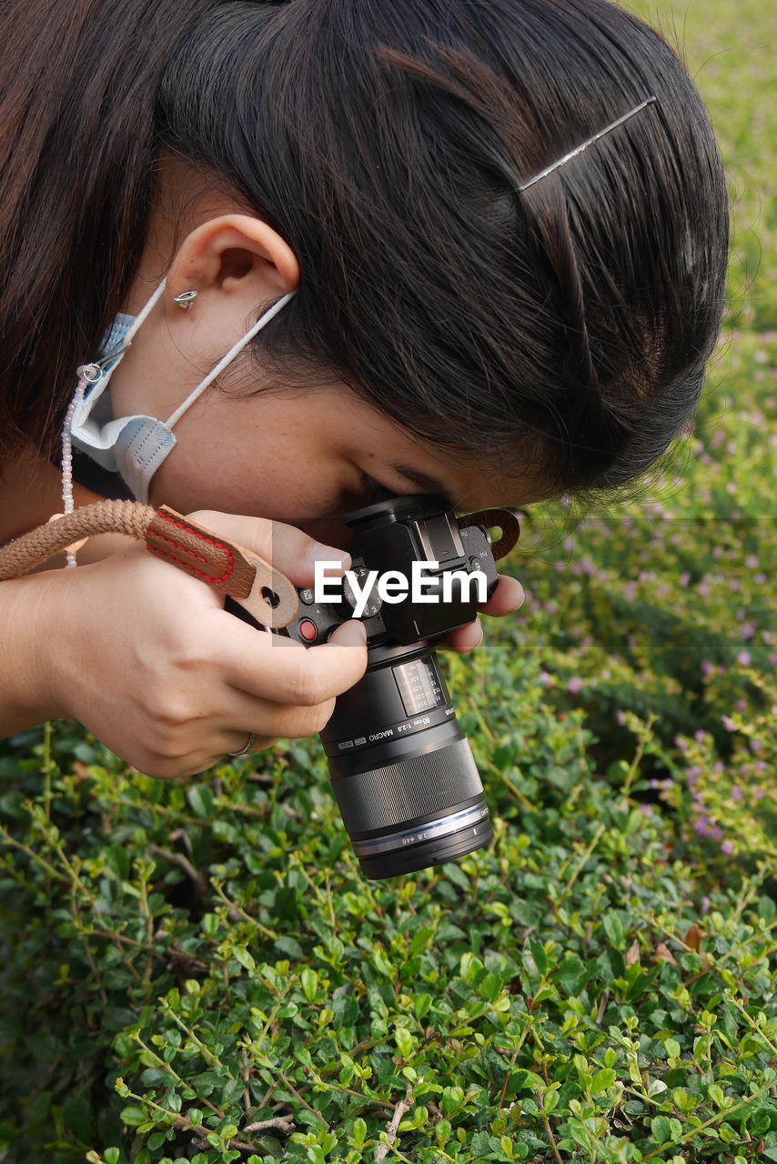 Portrait of woman holding camera on field