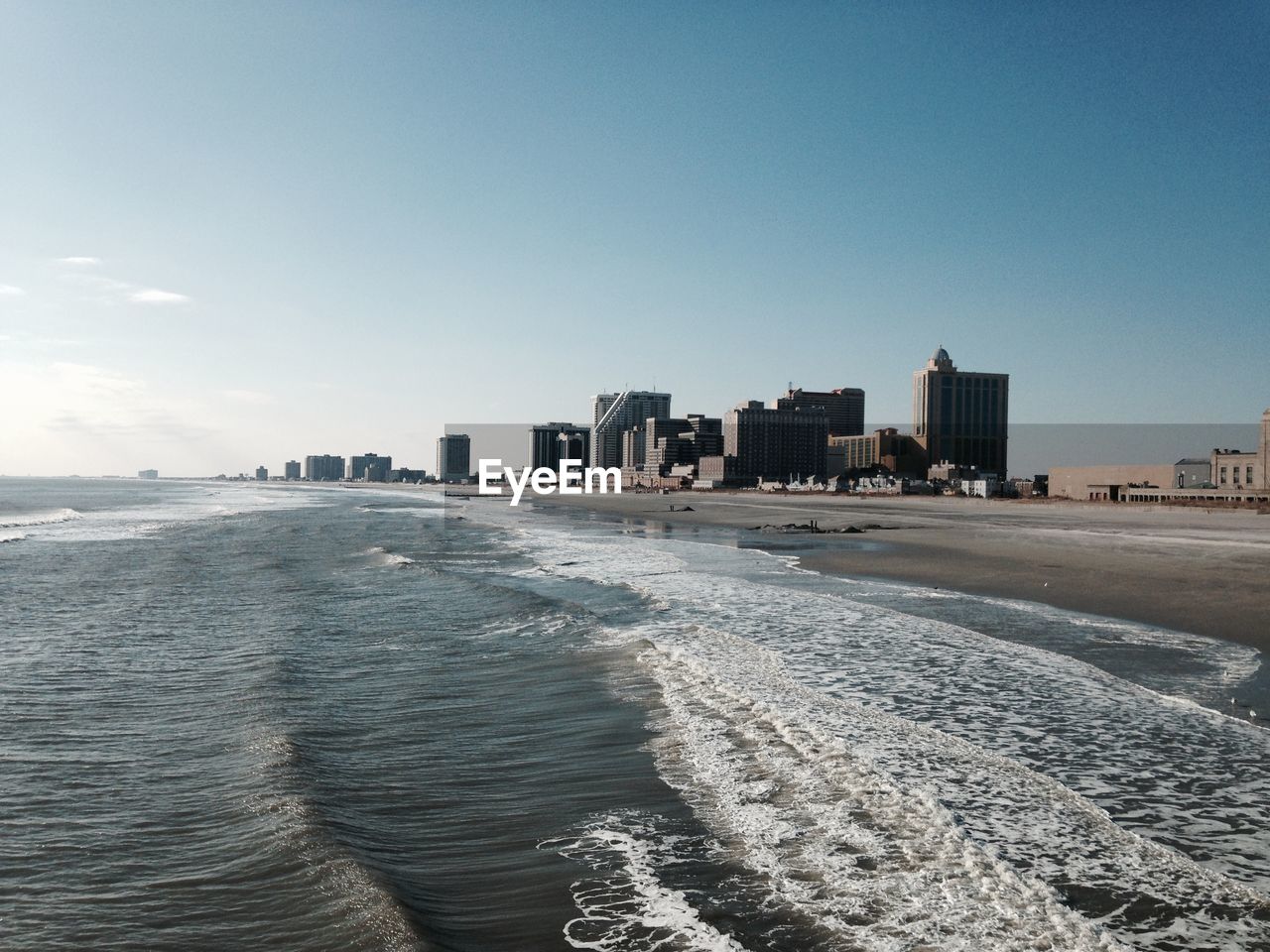 Scenic view of beach by city against sky