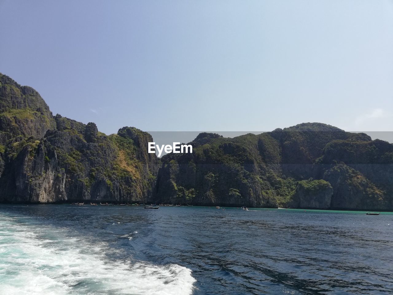 SCENIC VIEW OF SEA BY MOUNTAIN AGAINST CLEAR SKY