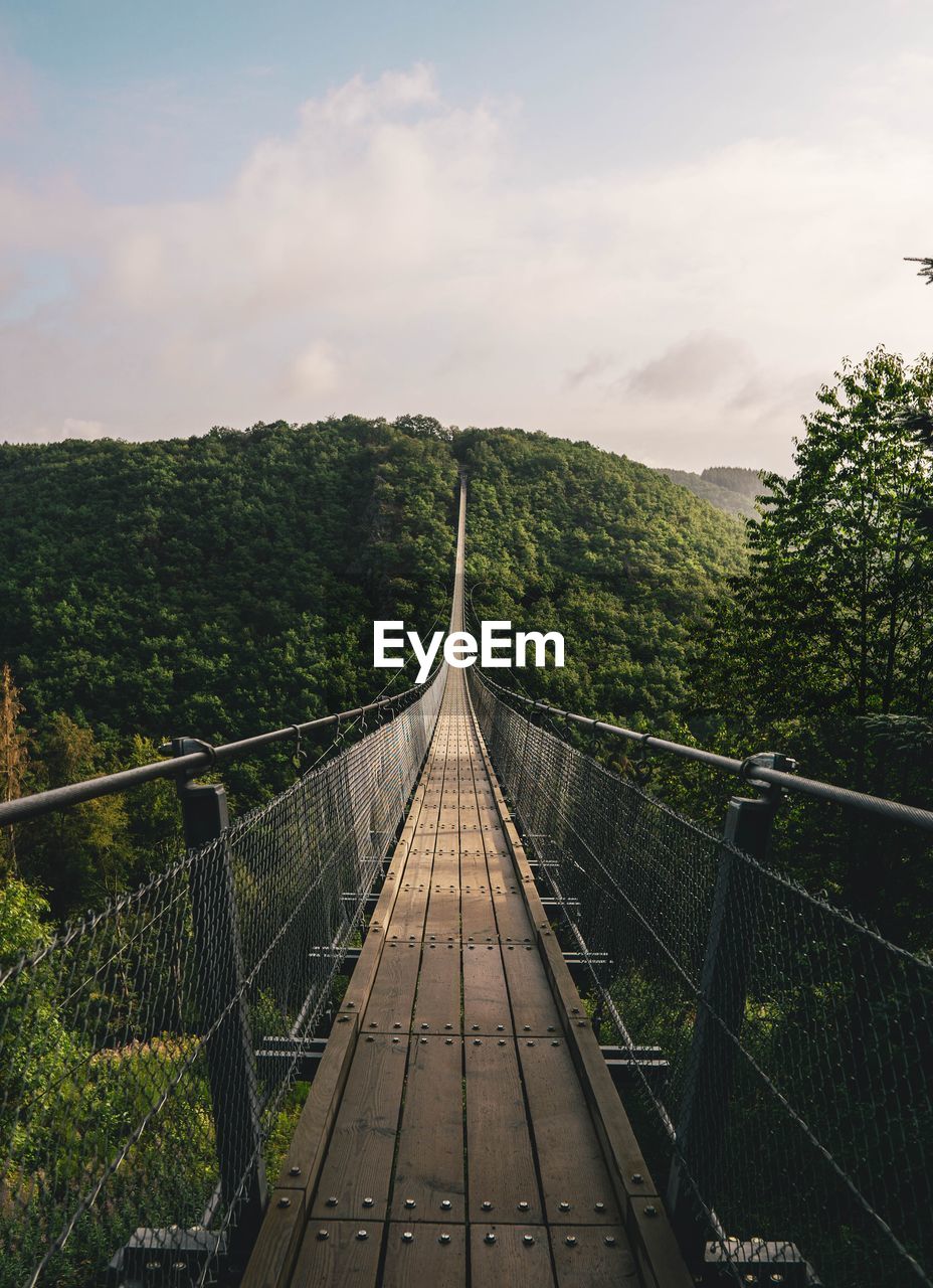 Brown wooden hanging bridge in the evergreen tropical forest over top