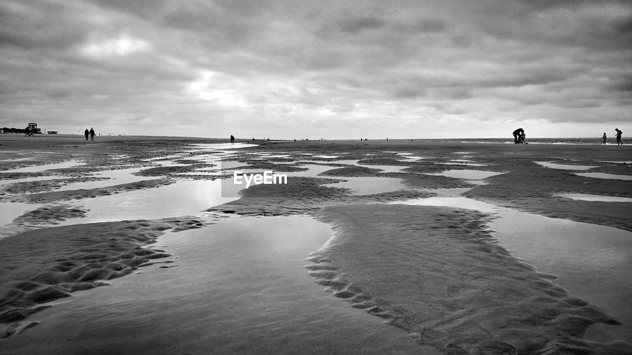 Scenic view of beach against cloudy sky