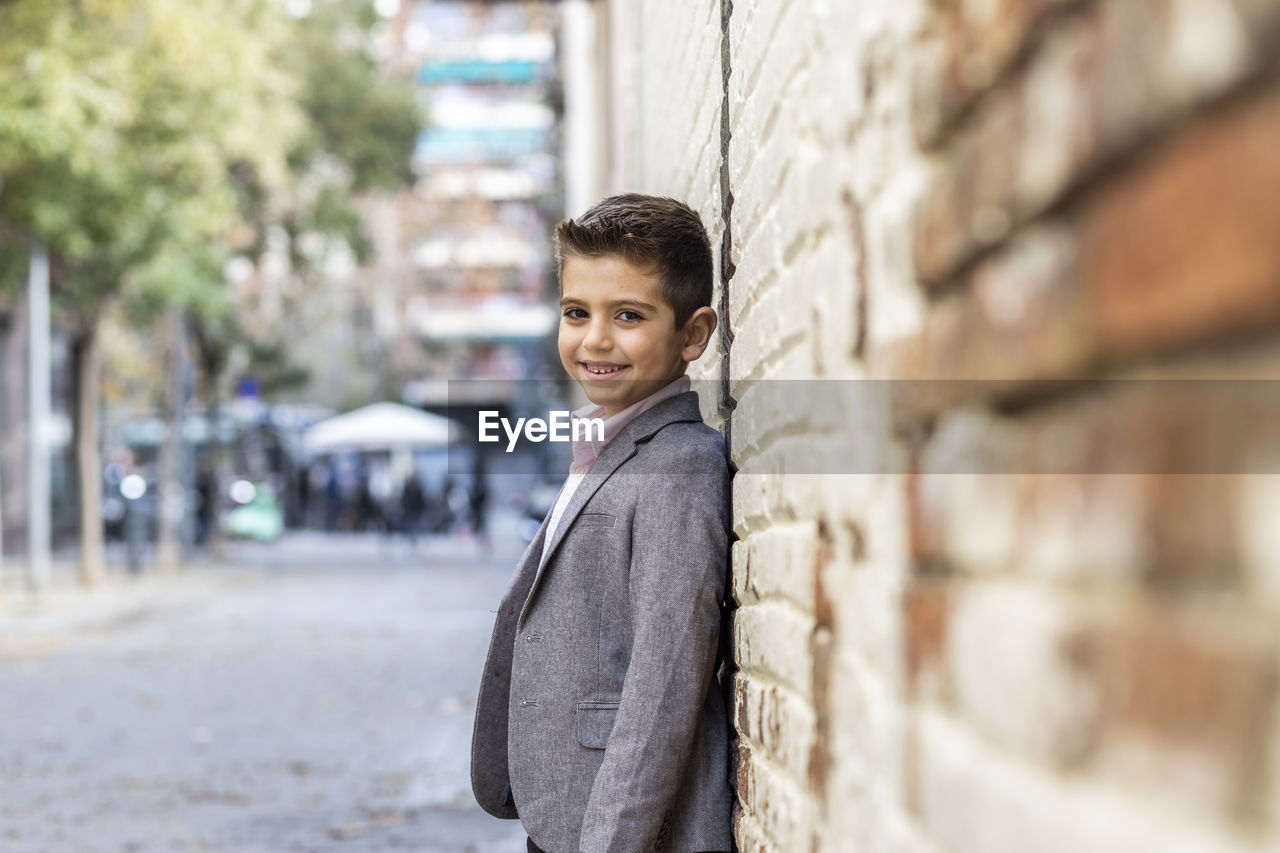 Portrait of boy standing against wall