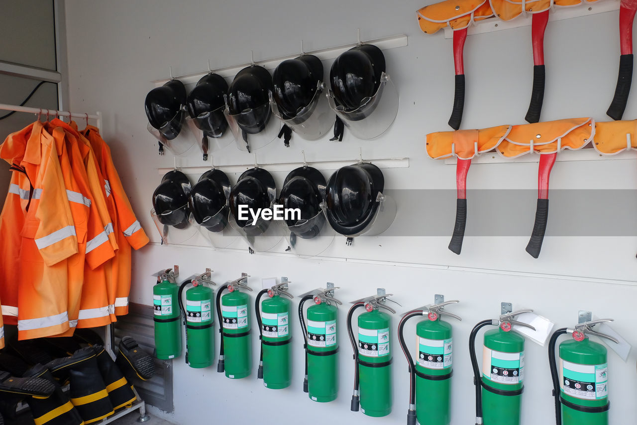 Fire extinguishers with helmets hanging on wall