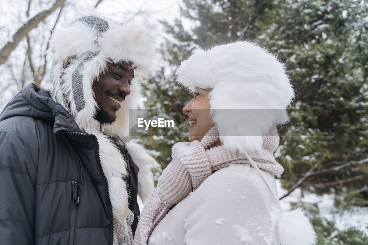 Heterosexual couple wearing fur hat standing in snow