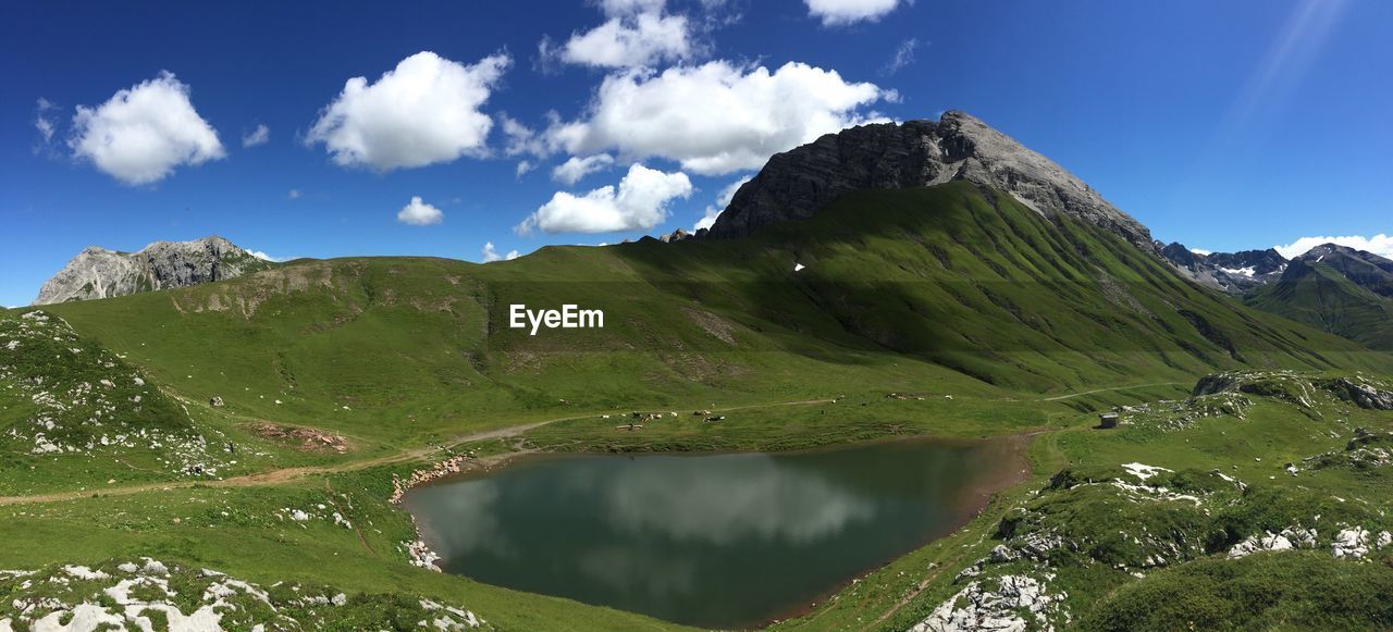 Scenic view of mountain by pond against sky