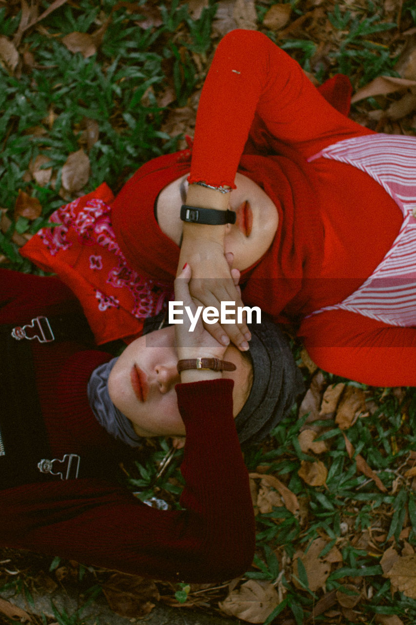 Directly above shot of female friends covering eyes with hands while lying down