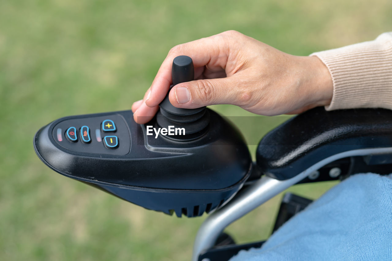 Asian lady woman patient on electric wheelchair with joystick and remote control  