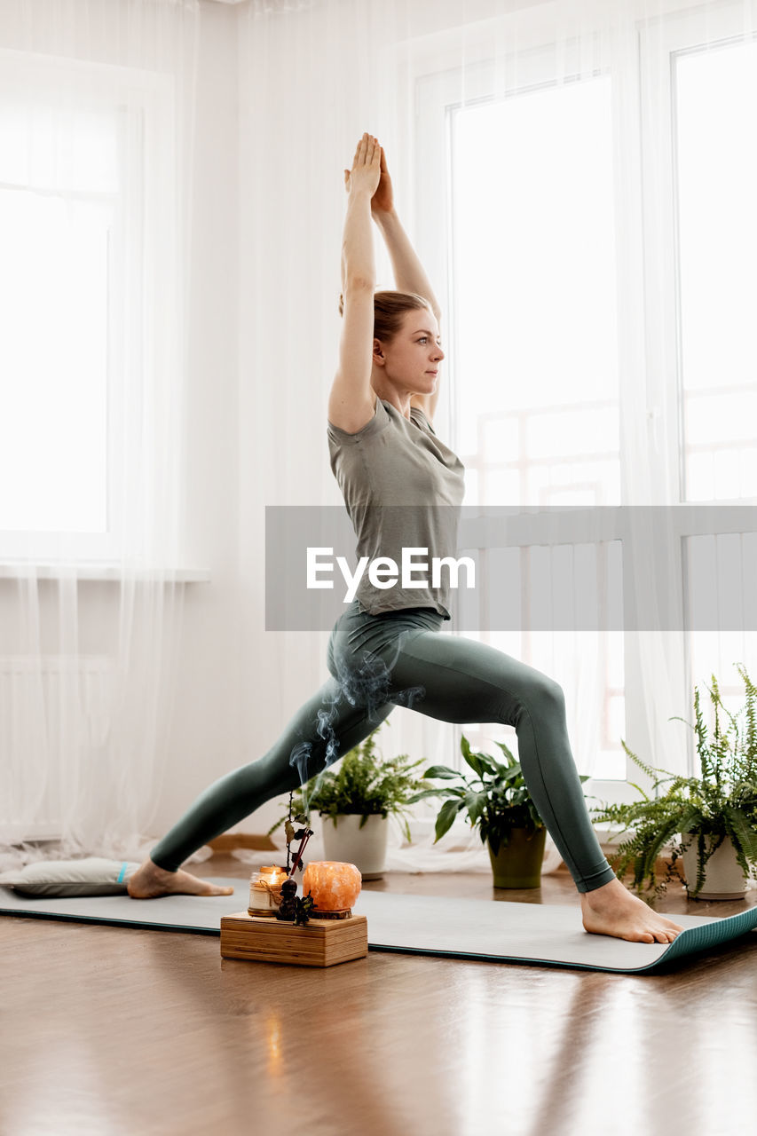 Beautiful young woman doing exercises and doing yoga at home