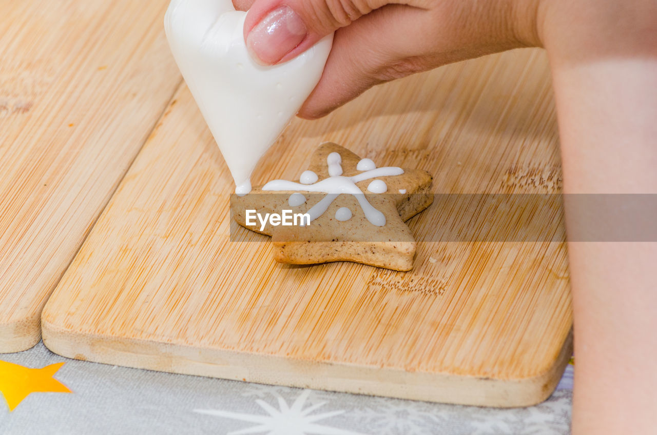 Cropped image of woman pouring cream on cookie