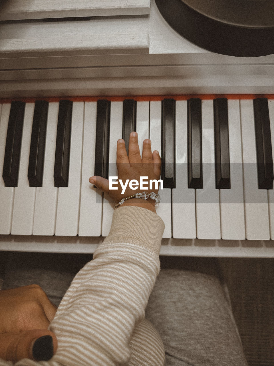 Cropped photo of woman holding baby while baby is playing piano