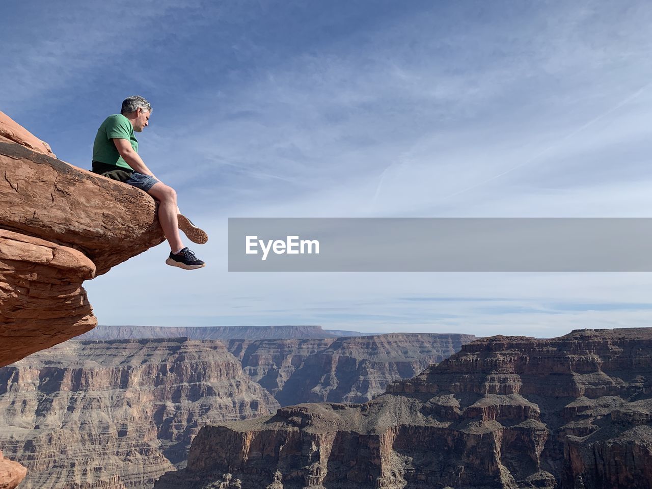 Side view of man on rock against sky