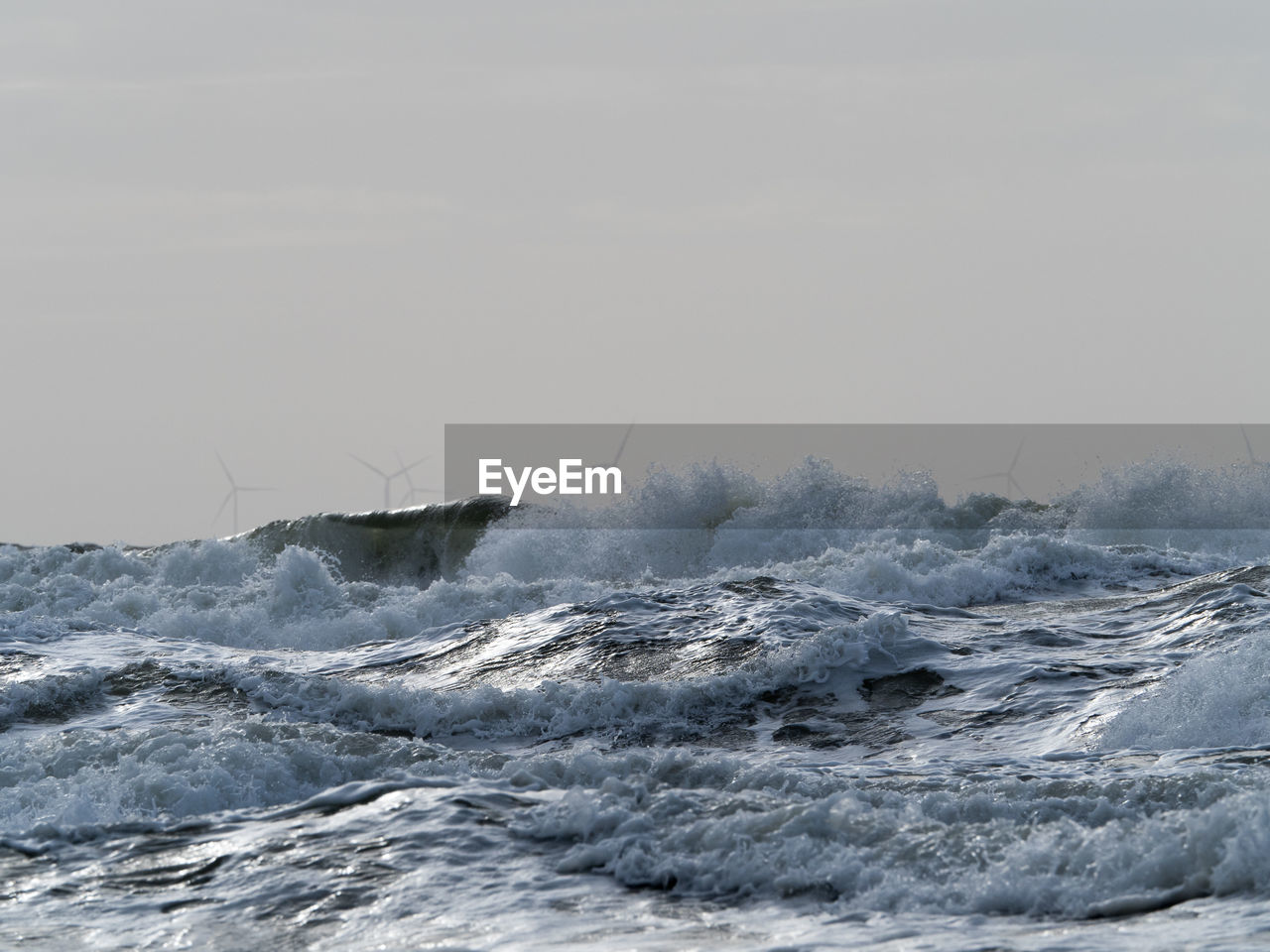 Waves splashing in sea against clear sky