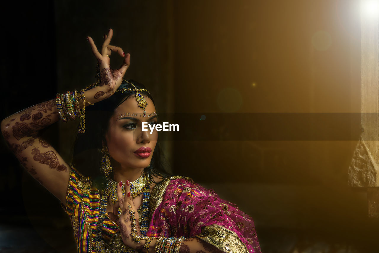 Woman in traditional clothing dancing against wall