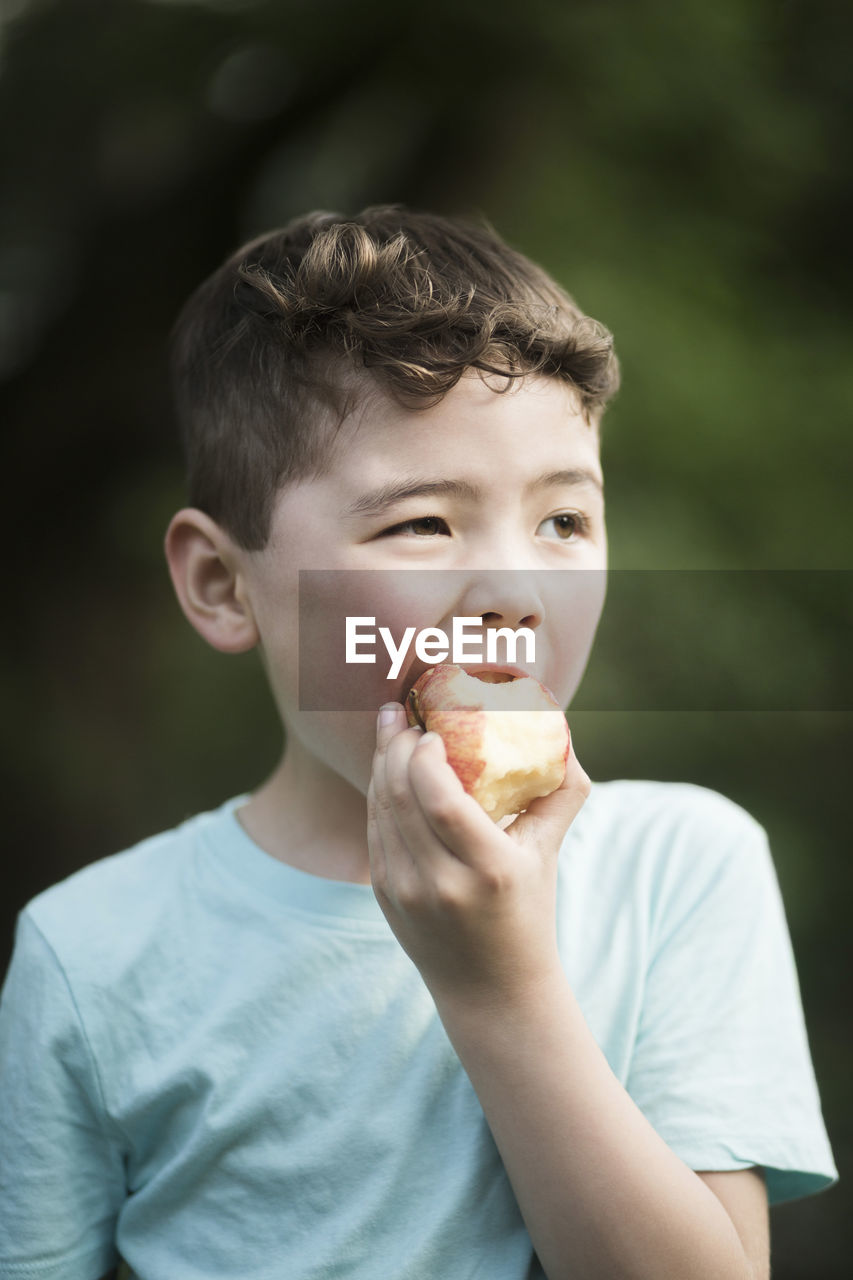 Boy eating apple while looking away