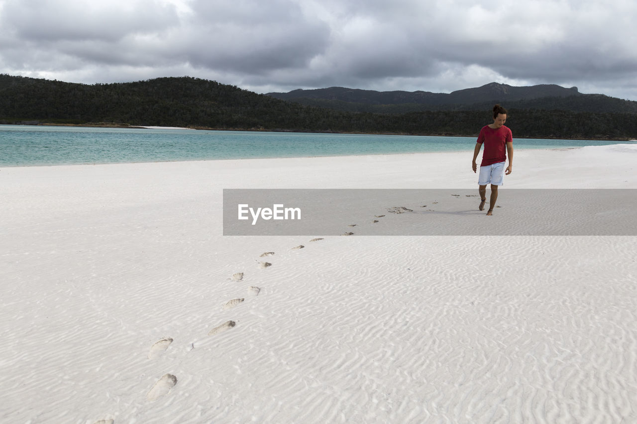 Tourist with a red shirt walking on white sandy australian beach