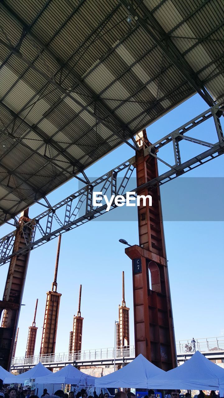 LOW ANGLE VIEW OF CRANE BY BUILDING AGAINST CLEAR SKY