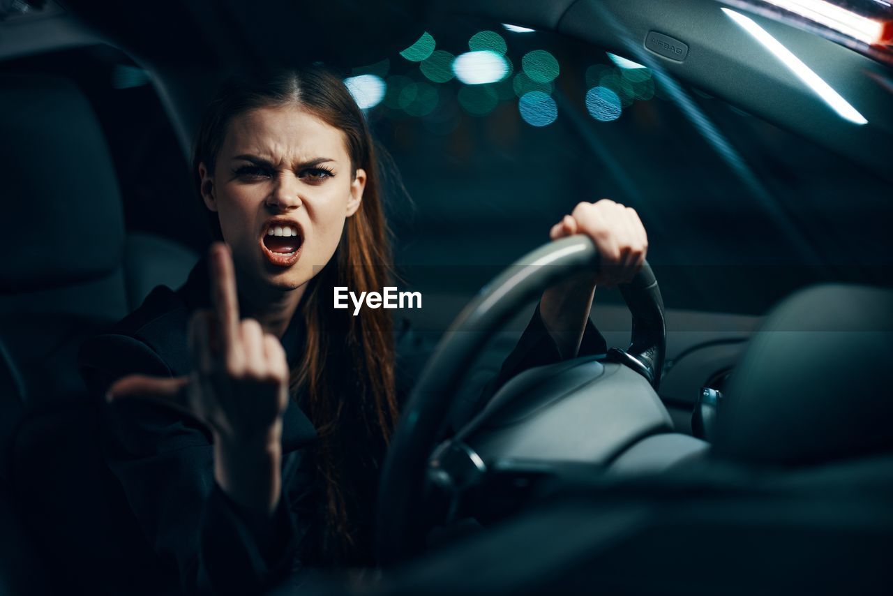 Woman showing middle finger sitting in car