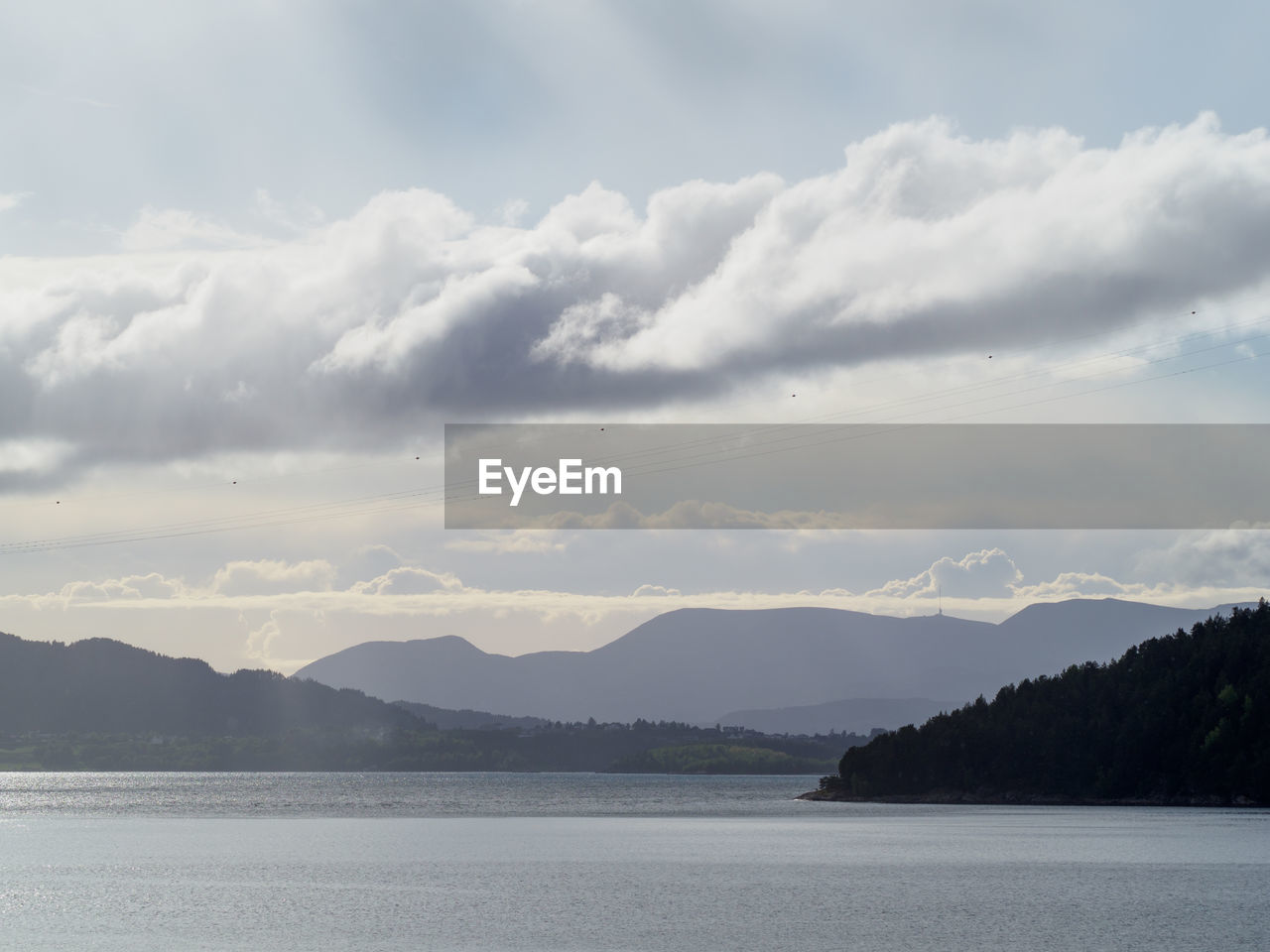 Scenic view of sea and mountains against cloudy sky