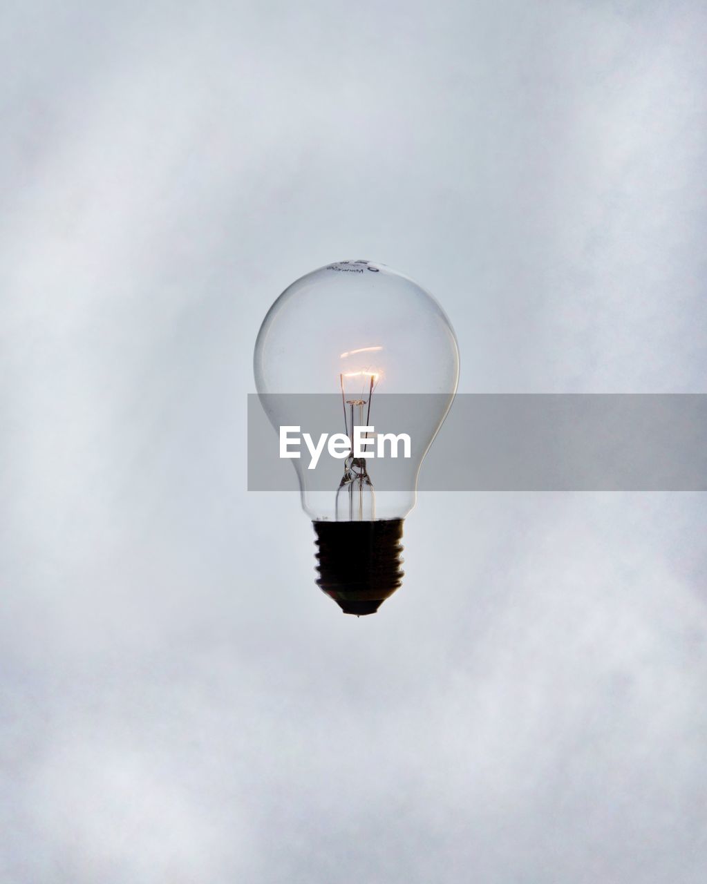 CLOSE-UP OF ILLUMINATED LIGHT BULB AGAINST SKY