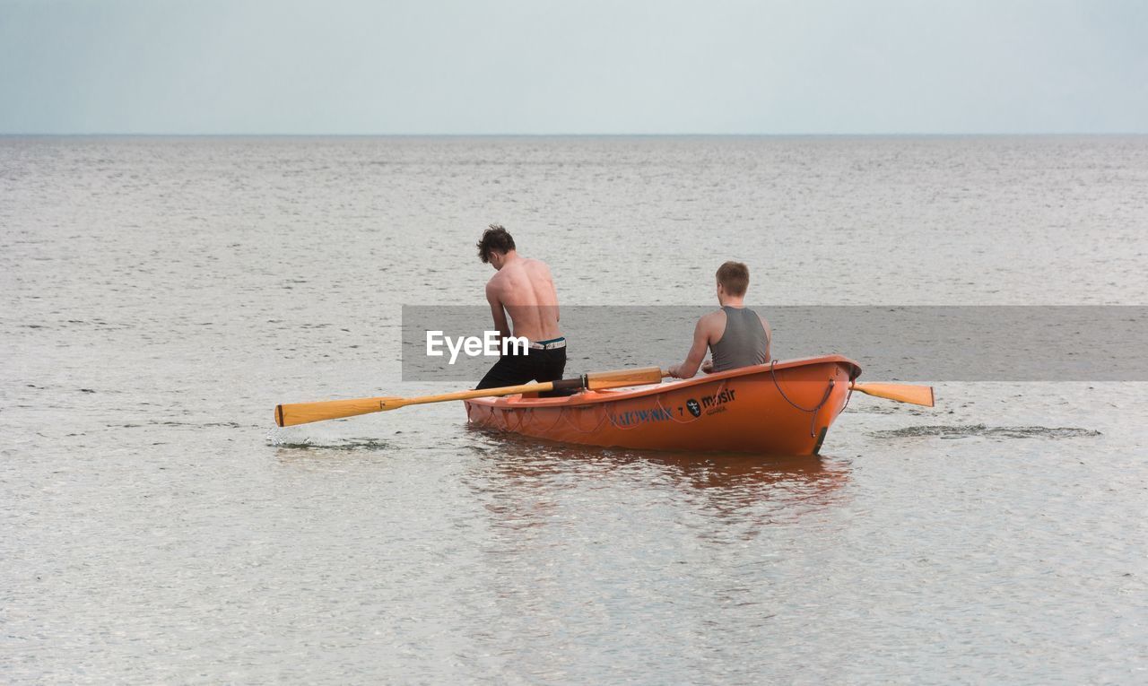 PEOPLE ON BOAT AT BEACH AGAINST SKY