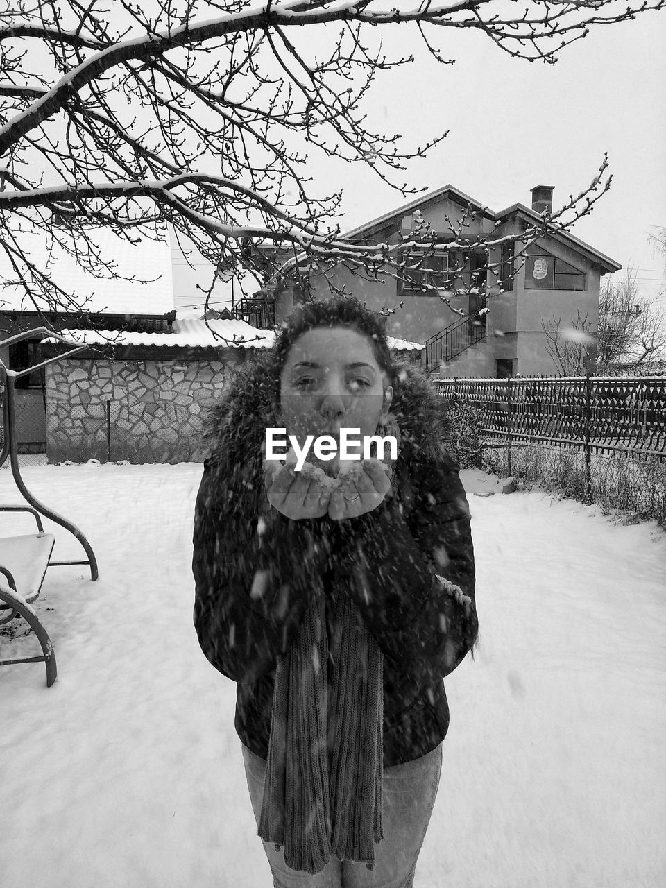 Young woman blowing snow during winter