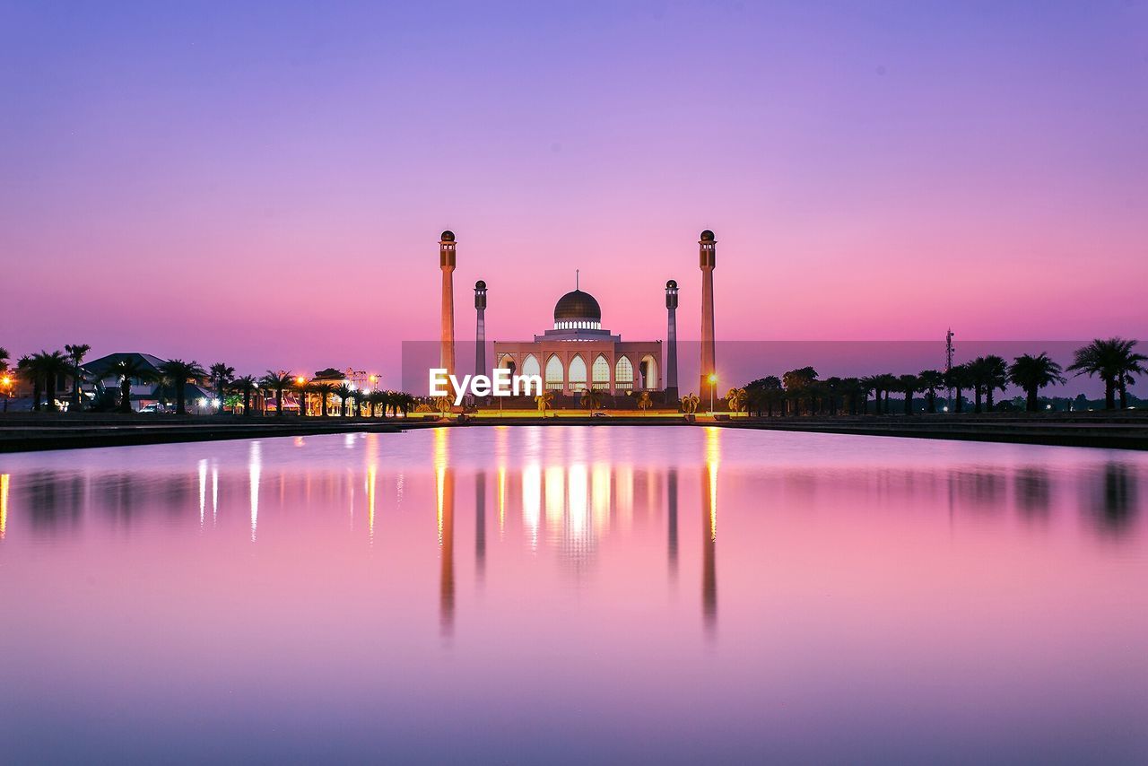 Songkhla central mosque by lake against sky during sunset 